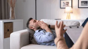 Strengthening Mental Resilience through Neuroplasticity Exercises A man laying on a couch receiving brain-based coaching from a professional, experiencing Mental Exhaustion and Fatigue
