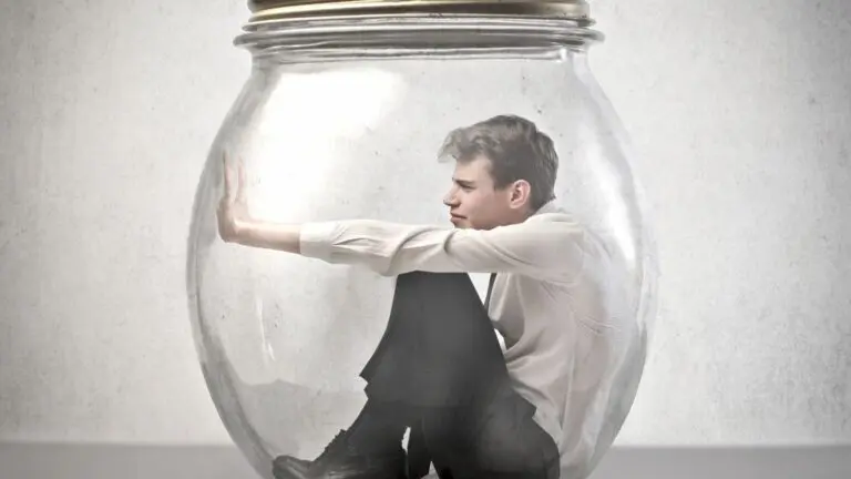 Man trapped inside a glass jar, pushing against the walls from his own mind traps.