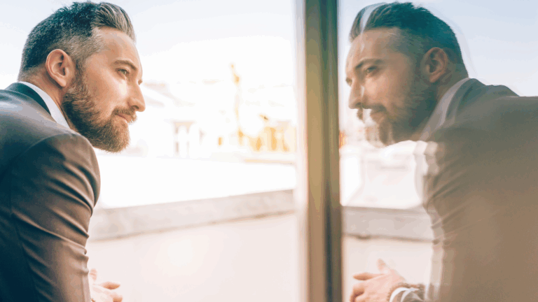 Man looking out window with Self-Awareness as he sees his reflection