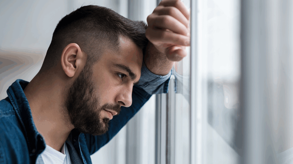 A person at a window experiencing loneliness, illustrating the neuroscience of feeling lonely