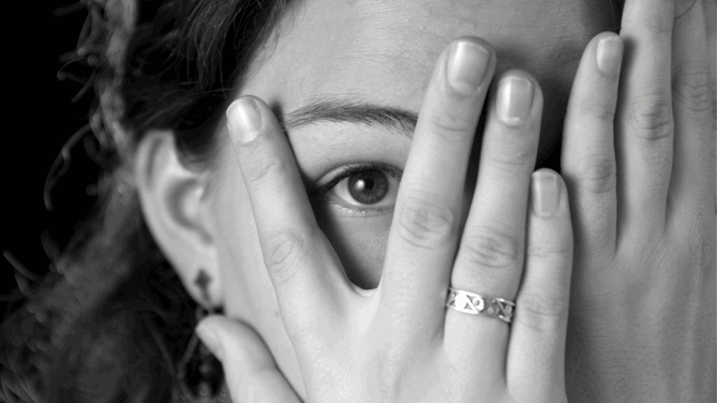 A woman covering her face in fear, representing fear of change and resistance to new situations.