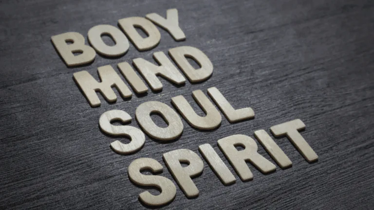 Wooden letters spelling "Body, Mind, Soul, Spirit" on a dark wooden surface. Wooden letters arranged on a dark wooden surface spell out the words "Body, Mind, Soul, Spirit," emphasizing the foundation of holistic psychology in addressing all aspects of human well-being.