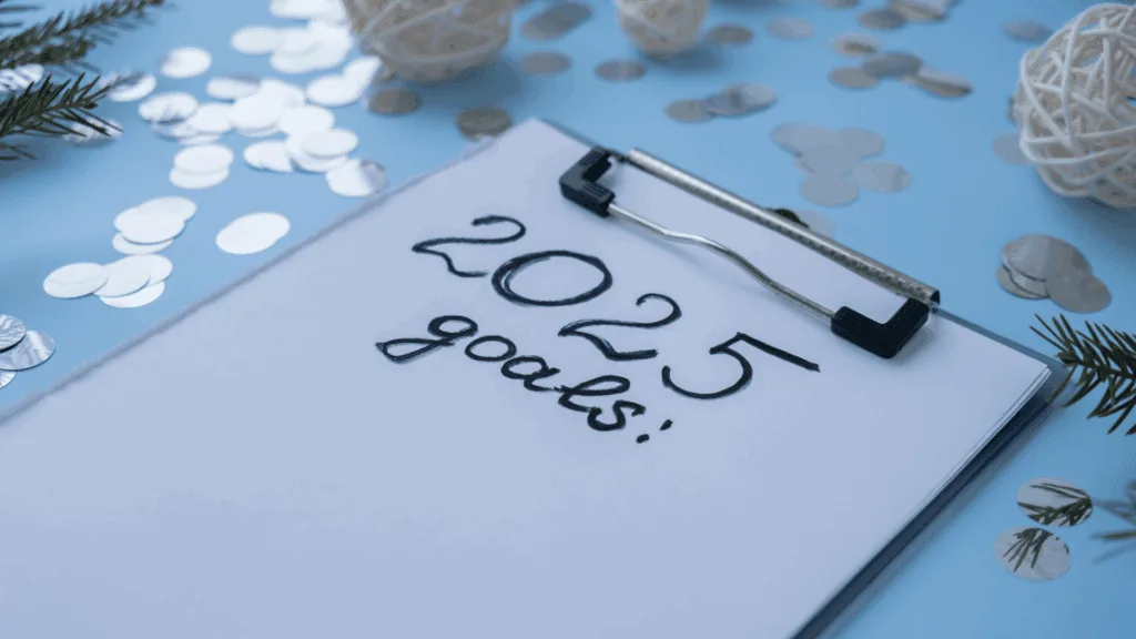 A clipboard with 2025 goals written on it, surrounded by confetti and festive decorations.