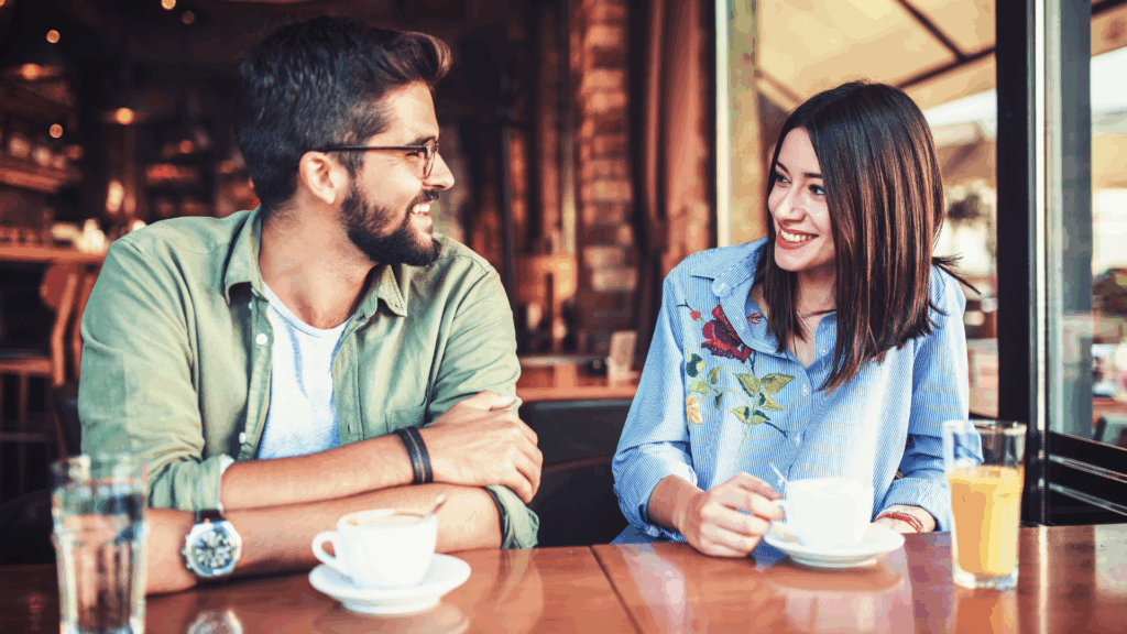 A couple smiling and enjoying a conversation over coffee.
