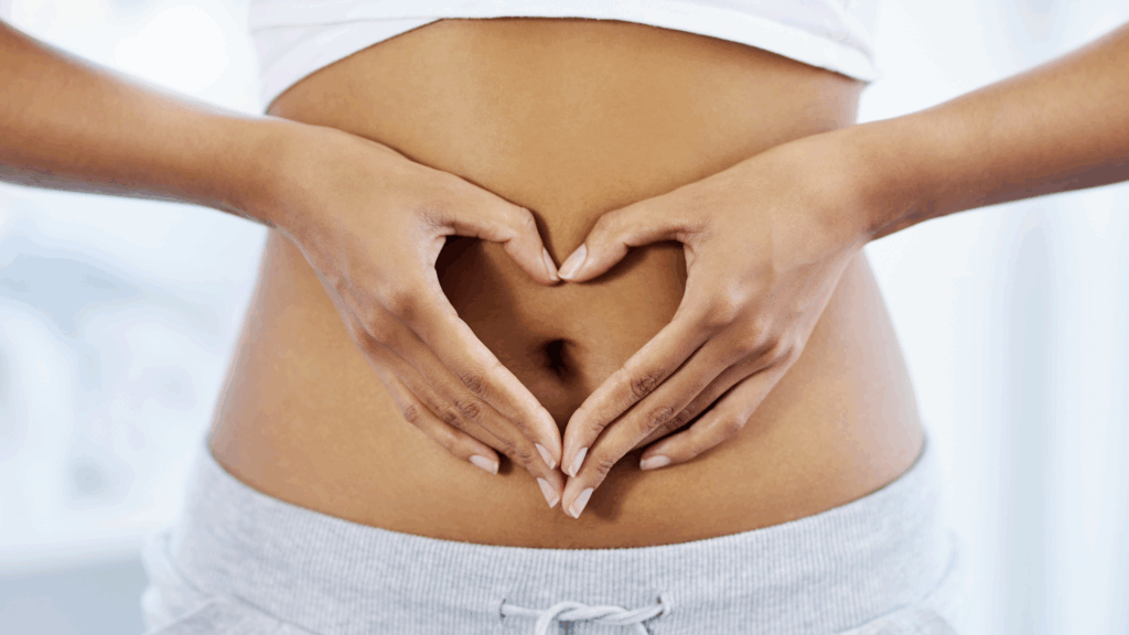 Hands forming heart shape on bare abdomen illustrating mind-gut connection.