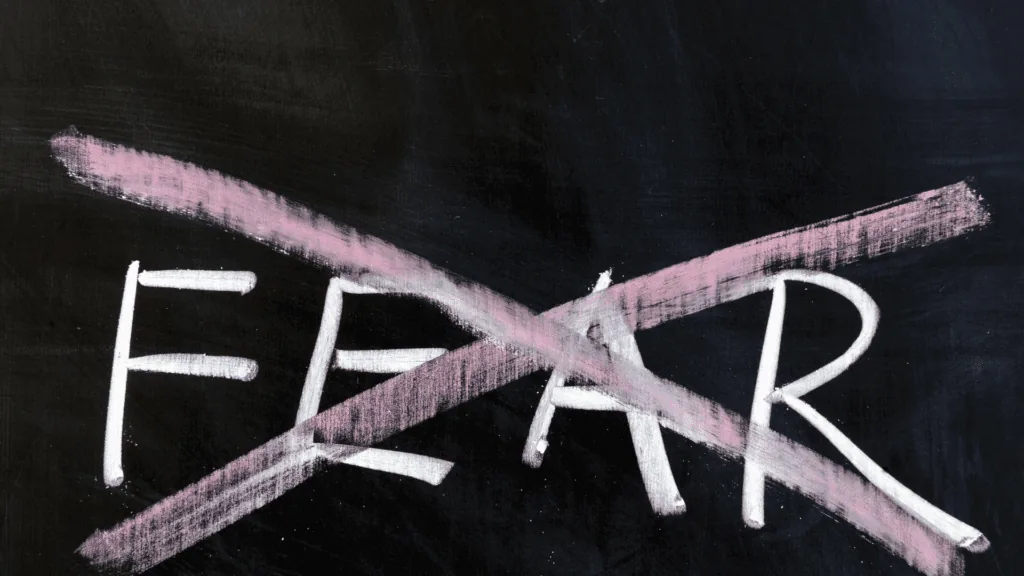 Fear' crossed out on a chalkboard, symbolizing overcoming fear and building resilience using neuroplastic momentum.