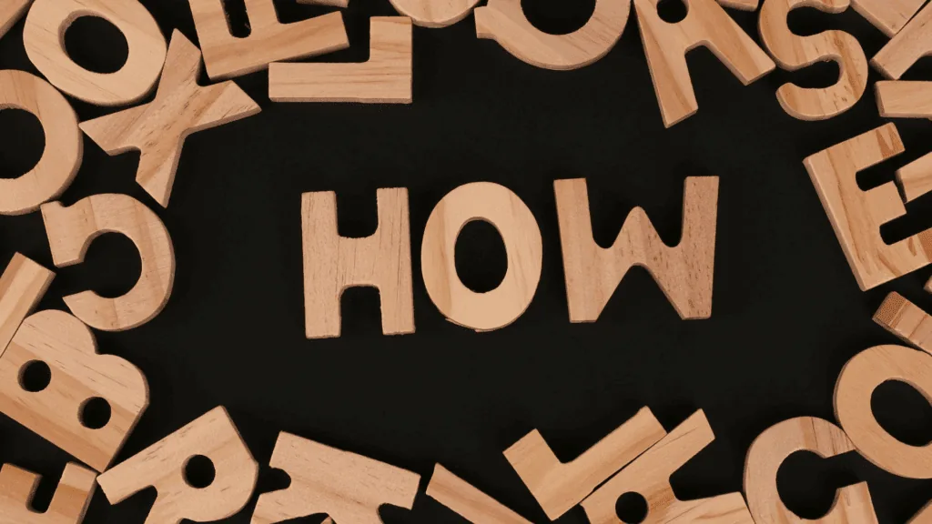 Wooden letters spelling the word how, symbolizing the process of understanding neuroplastic momentum and brain rewiring.