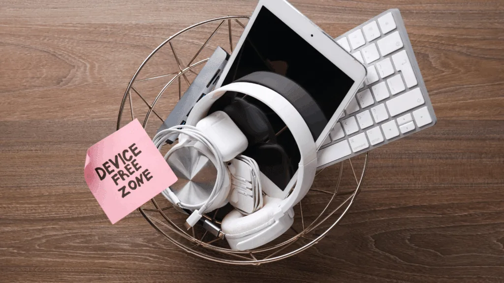 Basket filled with electronic devices beside a note reading device-free zone, representing a digital detox in practice.