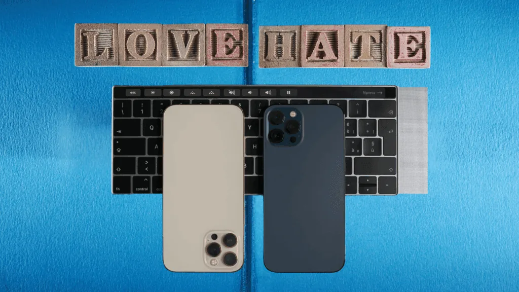Two smartphones on a laptop keyboard with wooden blocks spelling LOVE and HATE, symbolizing a conflicted relationship with technology and the need for a digital detox.