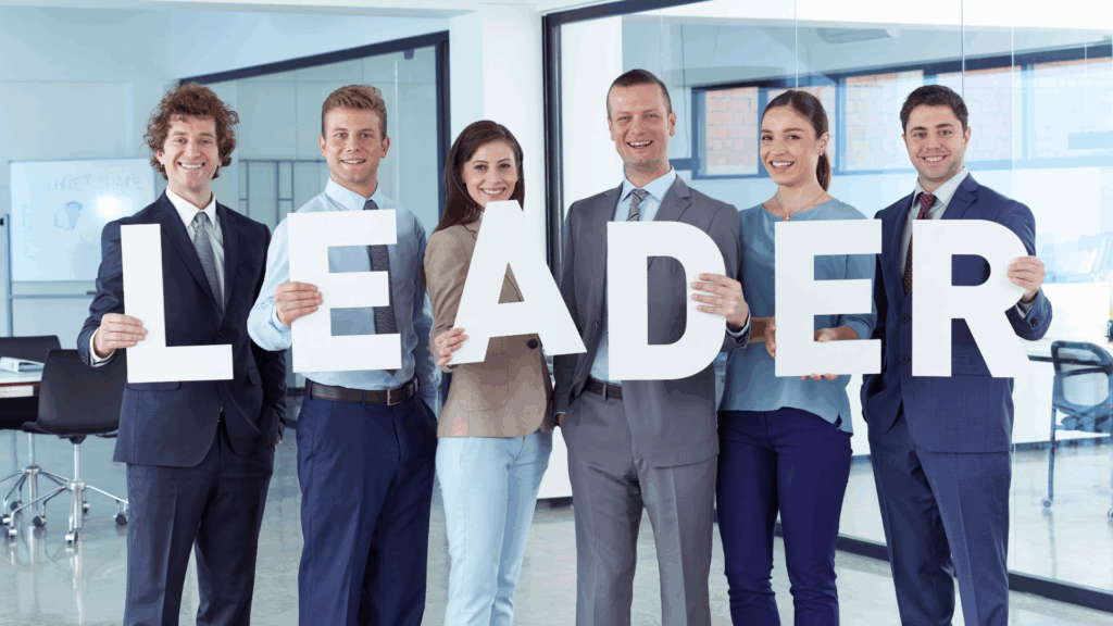 Professionals in business attire holding large letters spelling leader, representing executive presence in the workplace.