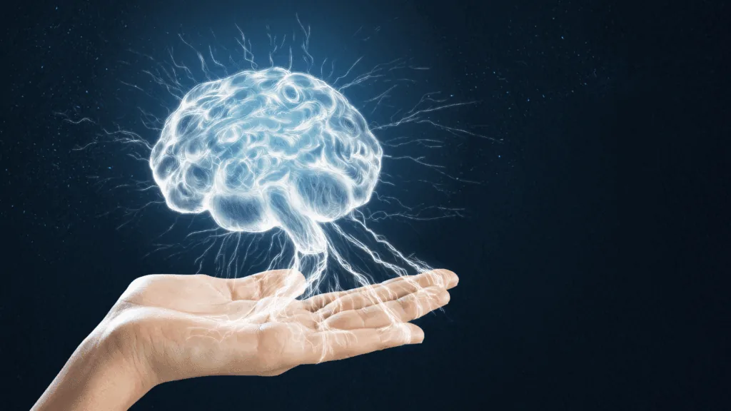 Open hand supporting an illuminated brain, symbolizing how the brain drives motivation and powers human achievement.

