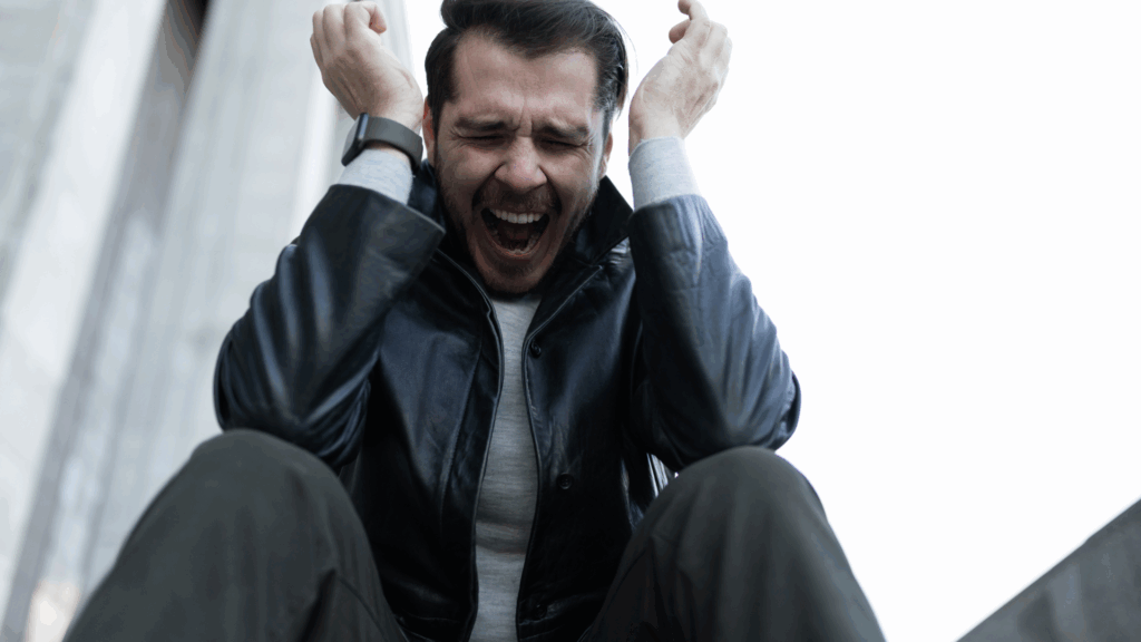 A person sitting outdoors with their head in their hands, in a moment of stress and reflection.