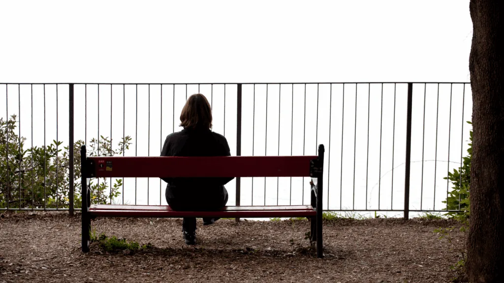 Person sitting alone on a bench, symbolizing isolation and loneliness in the neuroscience of sex addiction