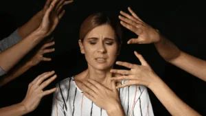 Woman feeling overwhelmed and distressed with many hands reaching toward her, symbolizing the struggles of anxious depression.