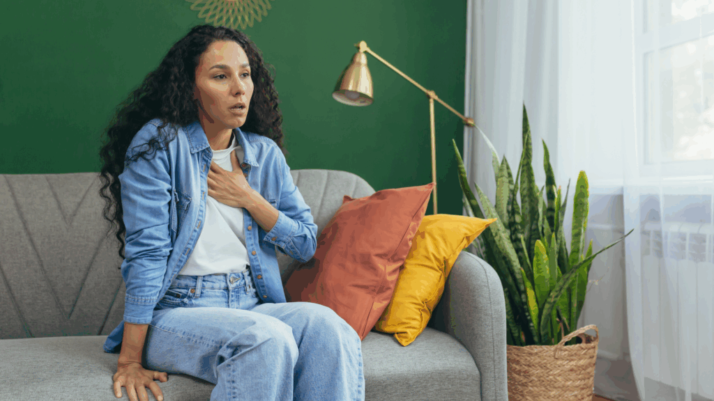 Woman practicing deep breathing on a couch, illustrating techniques for how do I stop a panic attack naturally.