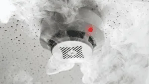 Smoke detector with red light triggered, symbolizing warning signals in compulsive cycles.