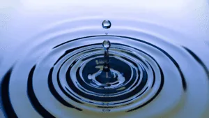 Water droplet creating ripples, symbolizing the neuroscience of micro-changes and small actions leading to wider effects.