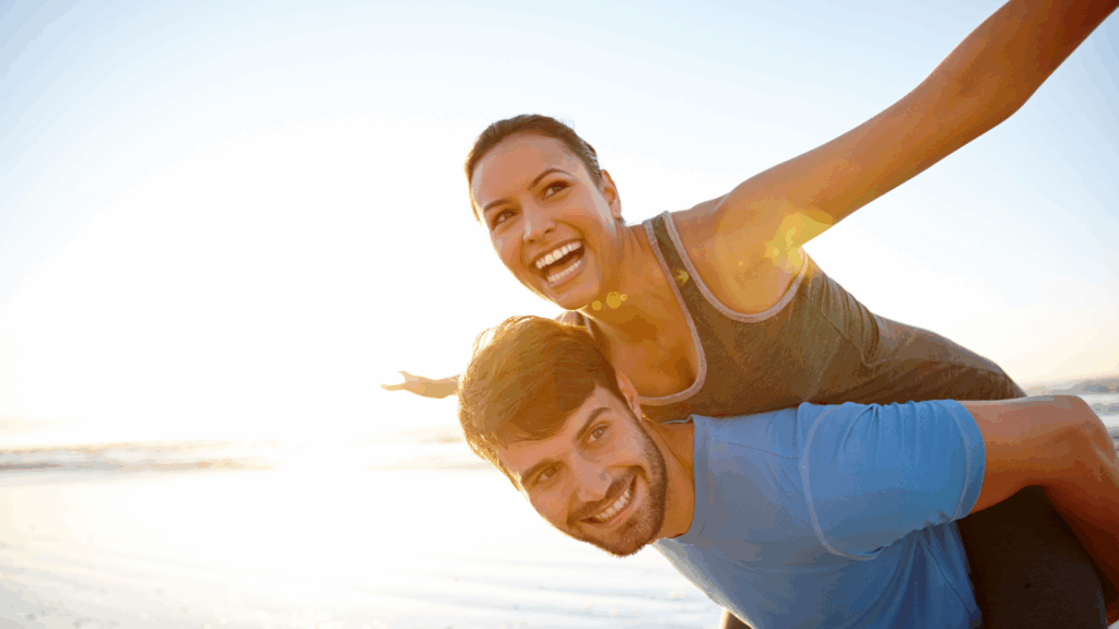 Joyful couple laughing at beach after overcoming feeling blah.
