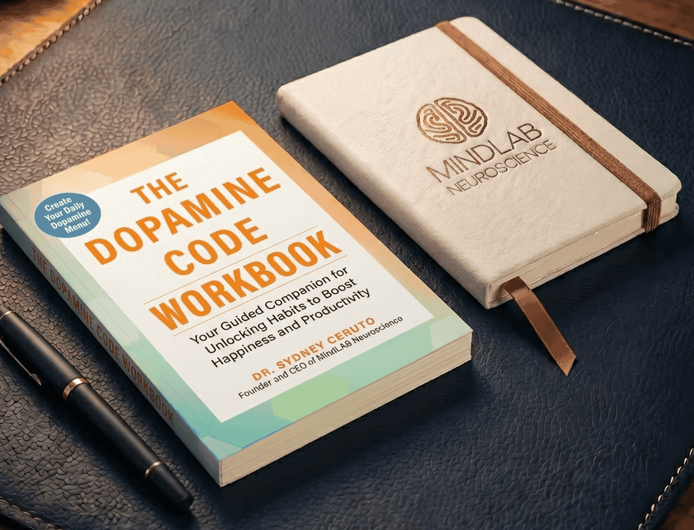 The Dopamine Code Workbook by Dr. Sydney Ceruto: a trade paperback on a navy blotter beside a copper-foil MindLAB journal