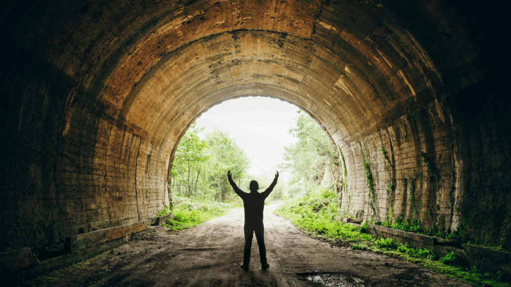 Victorious Man Overcoming Depression and Dysthymia: Understanding Key Differences and Finding a Solution Man in tunnel with arms raised in victory, symbolizing triumph over depression and dysthymia, and the importance of understanding their differences for successful recovery.