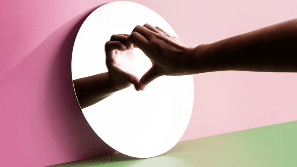 Conquering Relationship Phobia: A Journey Towards Love Hand making a heart symbol against a round mirror, signifying overcoming relationship phobia