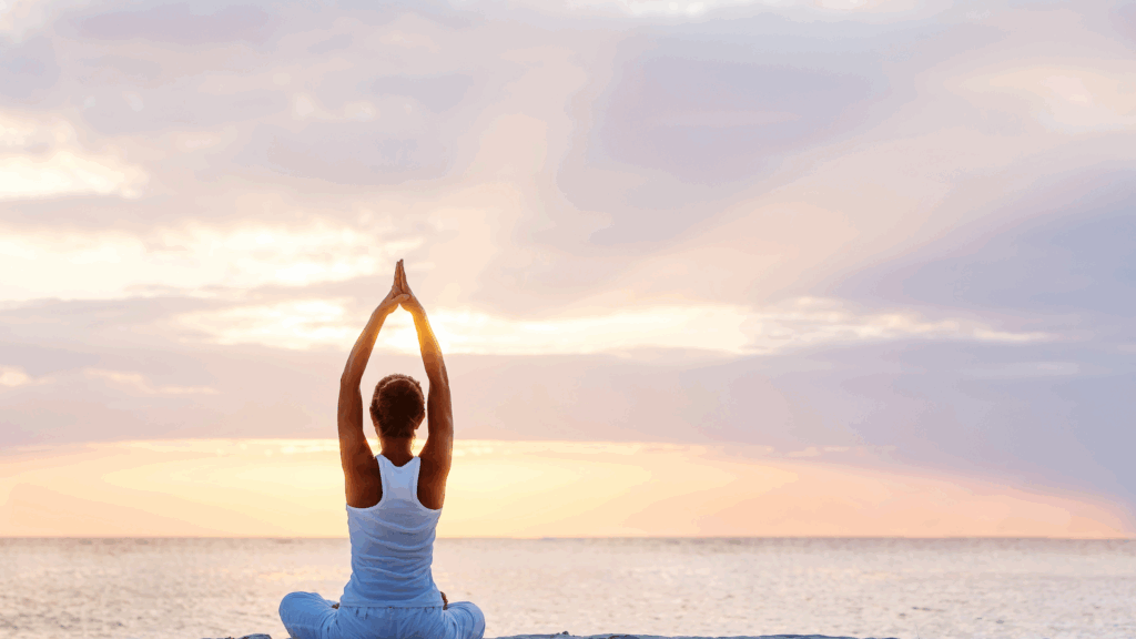 Woman practicing yoga at sunrise by the ocean, symbolizing the Dance of Neuroplasticity in mind-body connection.