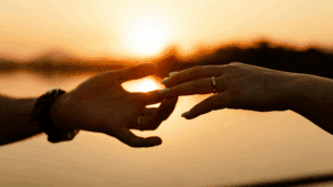 Two hands reaching for each other at sunset, symbolizing connection and the role of neuroscience in love biases.