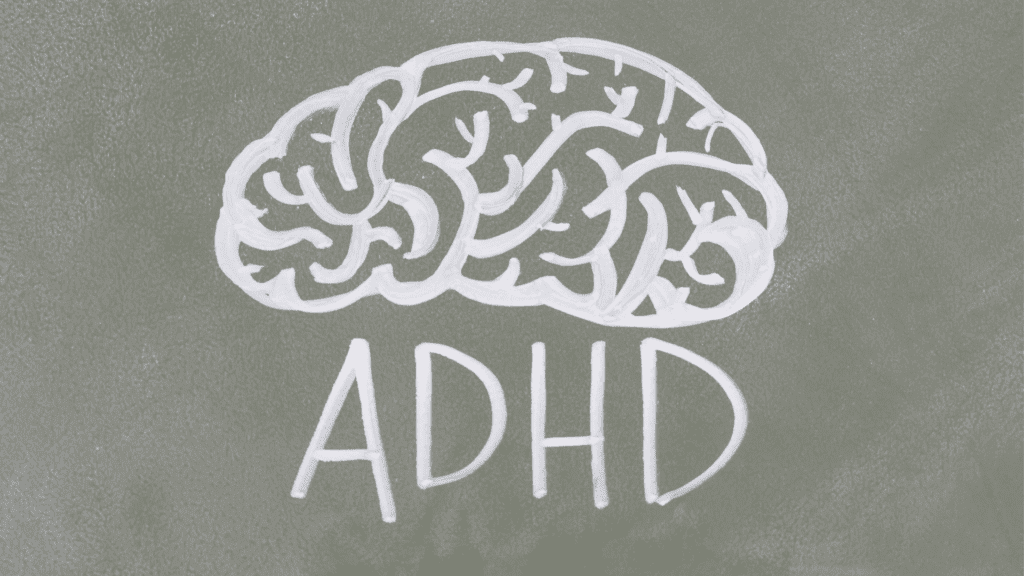a white brain drawn on a grey surface spelling out ADHD