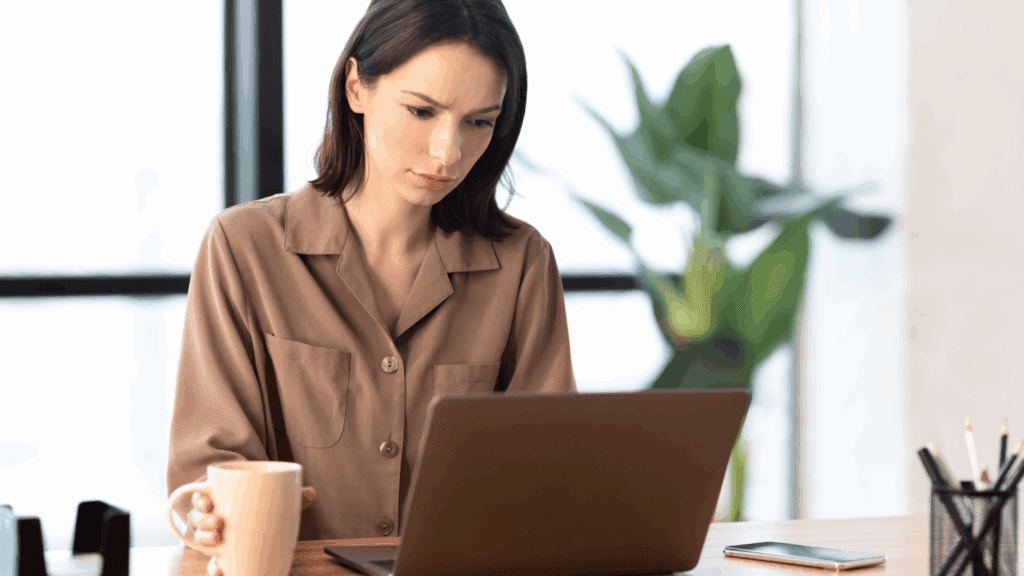 Woman working on a laptop researching Generative AI while holding a coffee mug.