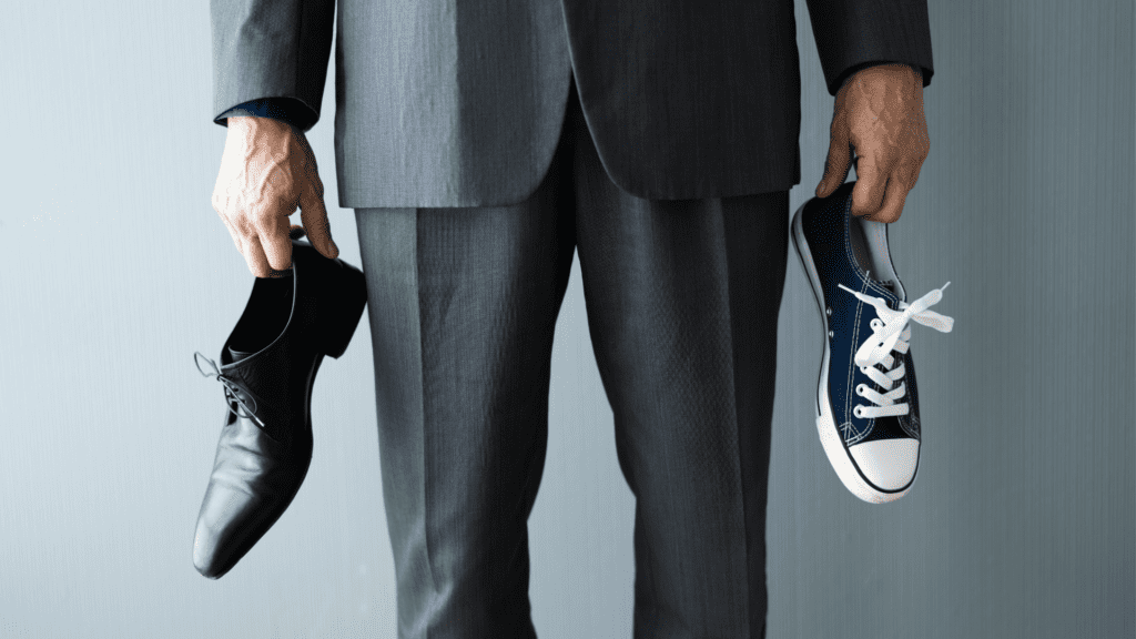a man holding one work shoe and one sneaker depicting the concept of compartmentalization.
