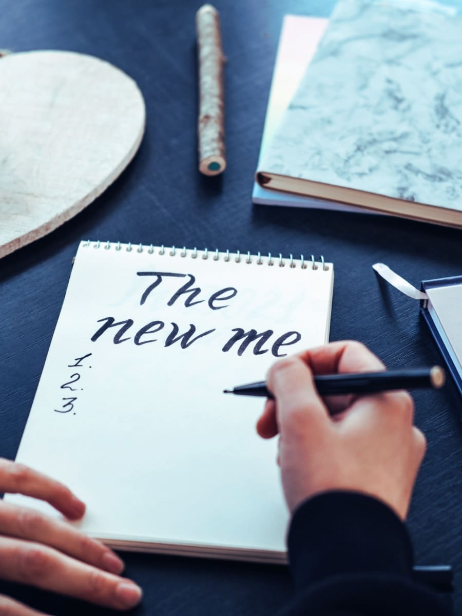 Process: hand writing 'The new me' in a notebook, symbolizing the MindLAB Neuroscience Process for personal reinvention and growth