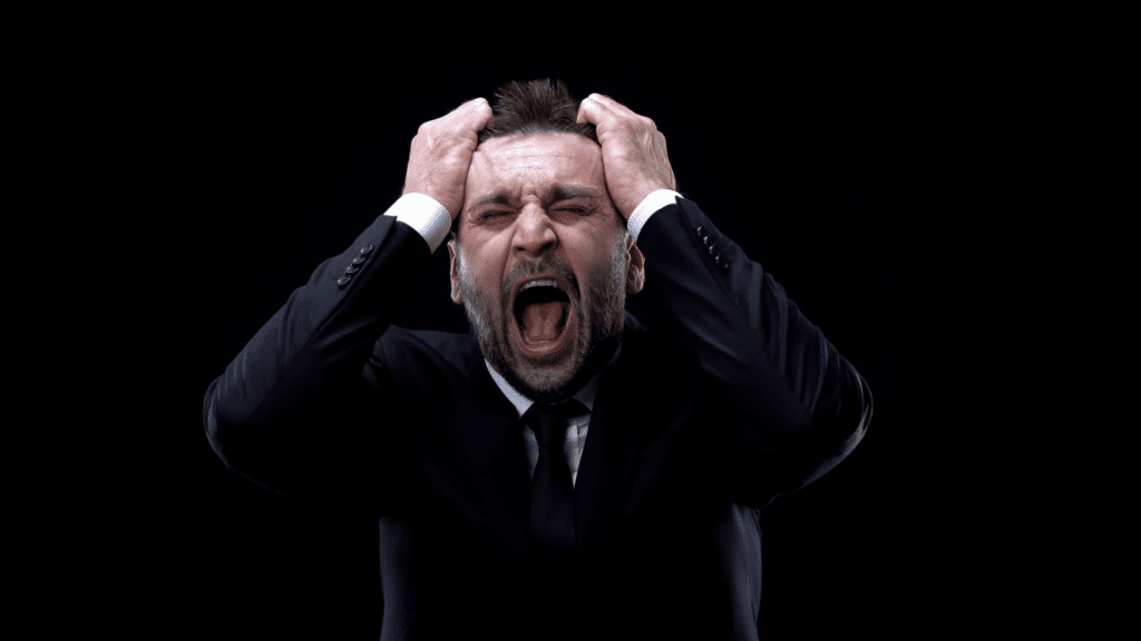 businessman experiencing severe mental exhaustion with hands clutching head