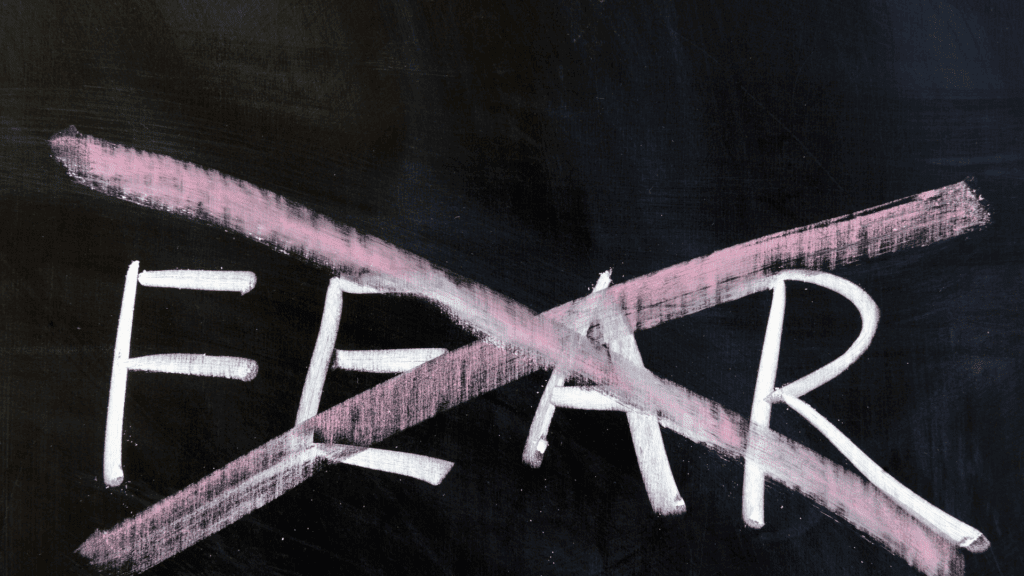 Fear' crossed out on a chalkboard, symbolizing overcoming fear and building resilience using neuroplastic momentum.


