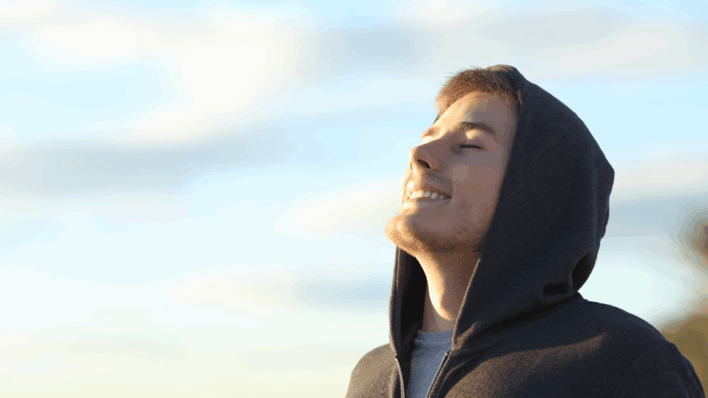 Young man with closed eyes looking upward peacefully, showing the calm achieved through mindfulness for anxiety.

