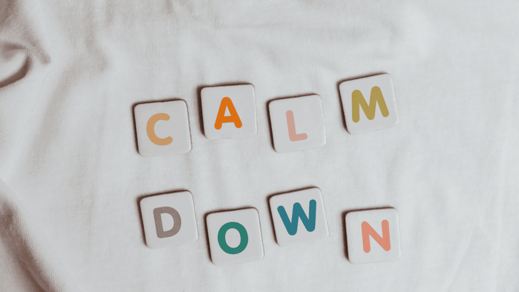 Tiles spelling out “calm down” on a white fabric background, symbolizing mindfulness of anxiety and emotional regulation.