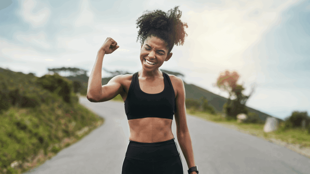 Fit woman flexing her arm outdoors as a symbol of strength and mindset mastery



