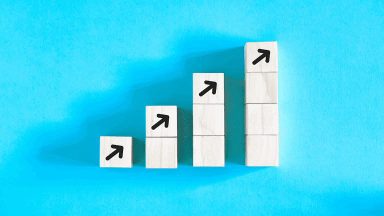 Wooden blocks stacked in ascending order with arrows pointing upward, symbolizing progress guided by a growth mindset coach.