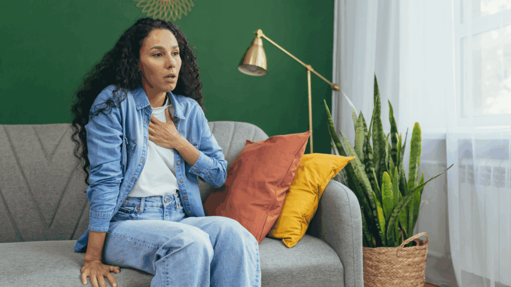 Woman practicing deep breathing on a couch, illustrating techniques for how do I stop a panic attack naturally.