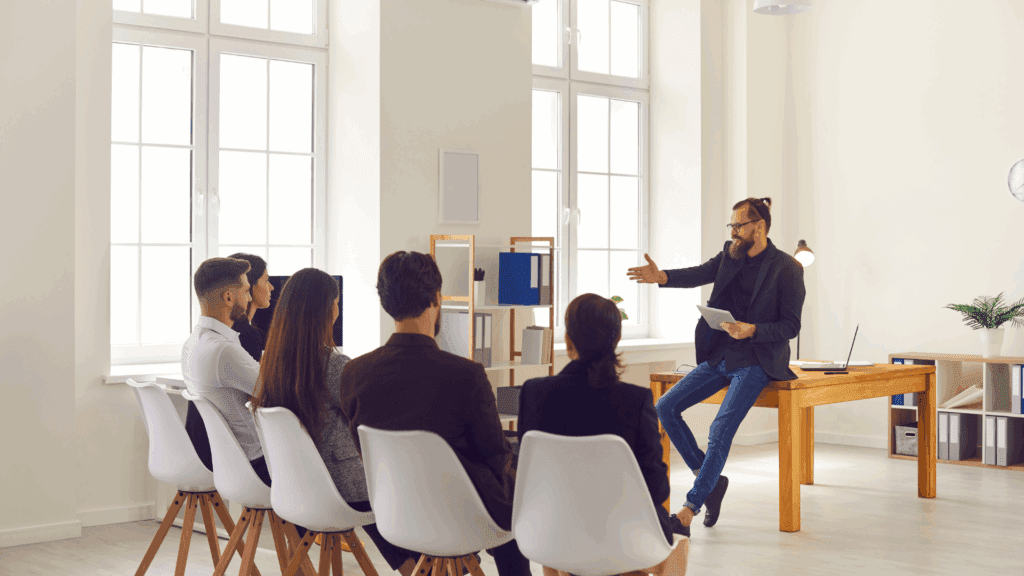 Man demonstrating leadership presence while leading a group discussion in a modern office setting.