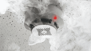 Smoke detector with red light triggered, symbolizing warning signals in the neuroscience of compulsivity.