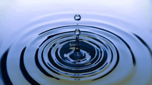 Water droplet creating ripples, symbolizing the neuroscience of micro-changes and small actions leading to wider effects.