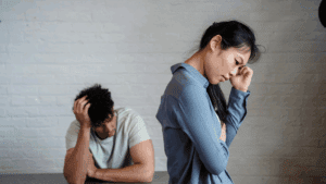 Couple sitting apart in distress, symbolizing the emotional pain of recovering from a break up.