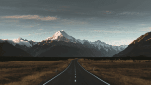 Open road leading to snow-capped mountains, symbolizing the journey of wanting versus needing in life goals.