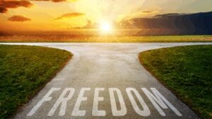 Pathway splitting under a sunrise with the word “freedom,” symbolizing the journey toward embracing your authentic self.