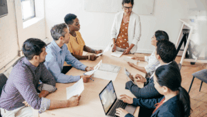 “Diverse business team in discussion around a meeting table, symbolizing balance and engagement in Dopamine-Aware Leadership.”