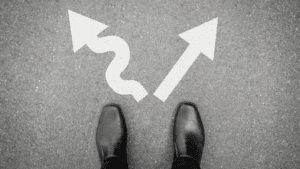 “Business shoes facing two arrows on pavement, symbolizing decision-making challenges addressed in Neuroscience-Based Executive Coaching.”