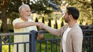 “Two neighbors shaking hands over a fence, symbolizing connection and trust built through Neuroscience-Based Executive Coaching.”