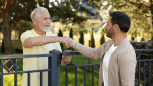 “Two neighbors shaking hands over a fence, symbolizing connection and trust built through Neuroscience-Based Executive Coaching.”