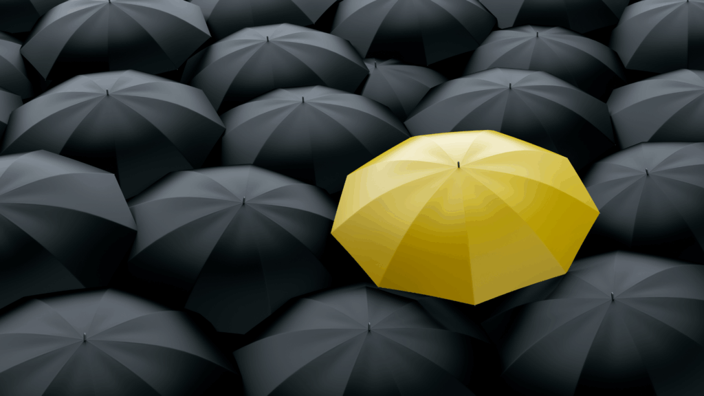 Yellow umbrella standing out among black umbrellas symbolizing differentiation in life coaching vs neuroscience coaching