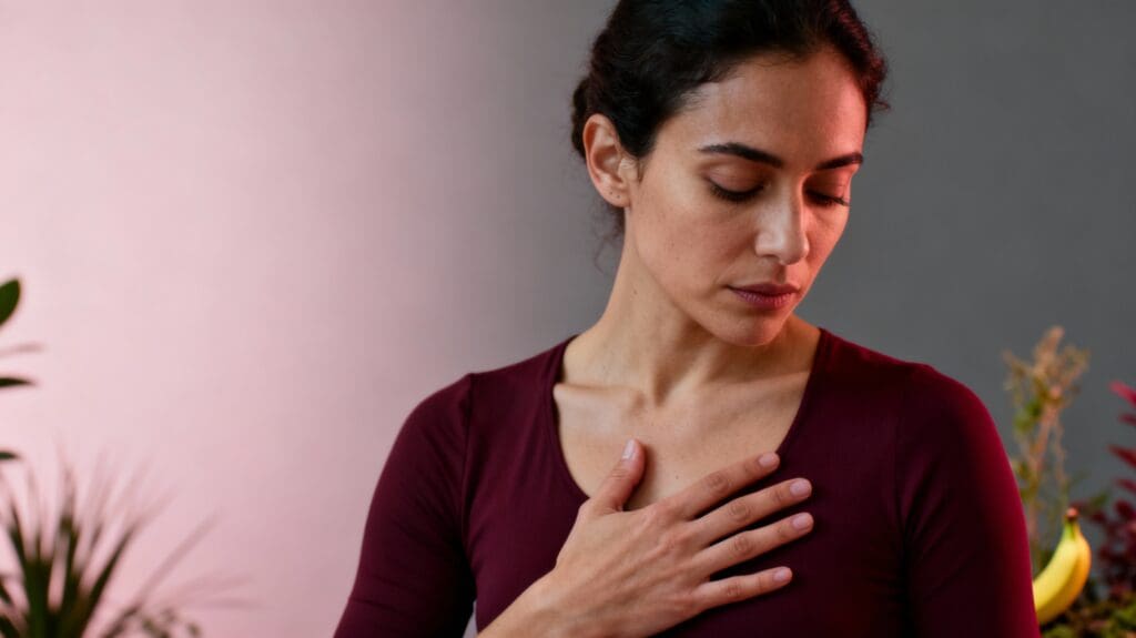 Woman with hand on heart in introspective moment listening to her nervous system and body wisdom signals about relationships